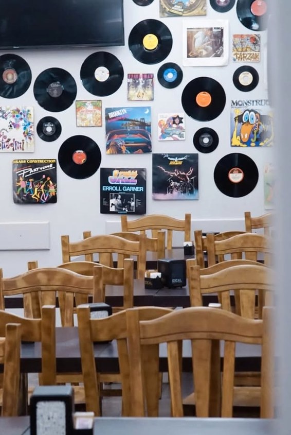 Tavoli in legno del pub a Como con il murale del van sulla parete